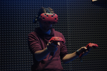 Man plays virtual reality using glasses, gamepad and headset.
