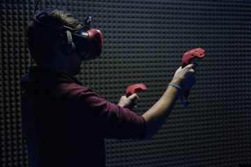 Man plays virtual reality using glasses, gamepad and headset.