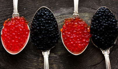 Red and Black caviar beads on silver spoon on wooden background.Top view