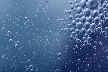 Blurred abstract background. Abstract blue circles and drops of different sizes, the texture of the liquid. Cropped shot, horizontal, blurred, free space, nobody, blue toning.