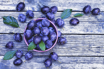 plums in a cup close-up. plums on a wooden background. the view from the top. copy space.