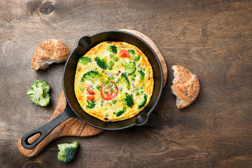 Baked omelette with green vegetables- broccoli, sweet pea and tomato in a skillet .