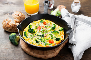 Baked omelette with green vegetables- broccoli, sweet pea and tomato in a skillet .