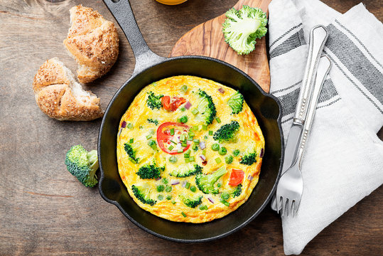 Baked omelette with green vegetables- broccoli, sweet pea and tomato in a skillet .