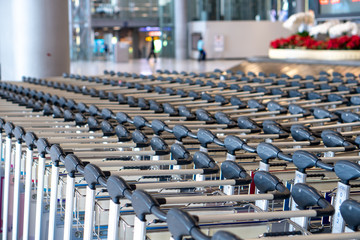 Close up many row of empty luggage trolleys in airport with blurred background.