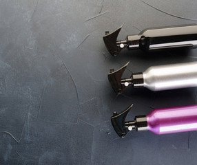 Three multicolored bottles of professional hair spray on dark  background