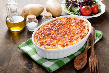 Potato casserole with meat on  wooden table.