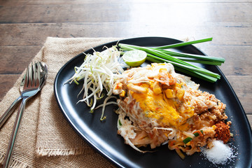 Pad Thai or stir-fried noodles with shrimp and egg on black plate. Thai food