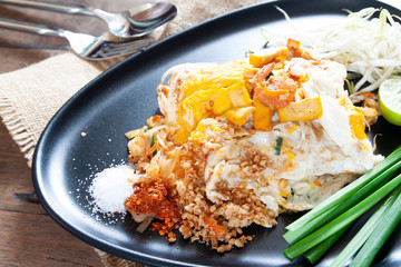 Pad Thai or stir-fried noodles with shrimp and egg on black plate