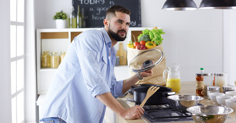 Smiling and confident chef standing in a large kitchen tasting 