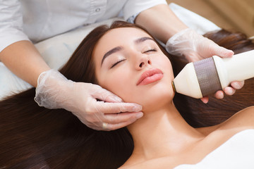 The procedure of photoepilation in the beauty salon. A young woman is removed unwanted hair on her face. Hardware cosmetology. Microcurrent therapy. Close up