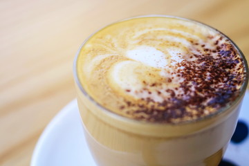 Hot latte juice in a glass with a white coaster with a wooden spoon placed on a beautiful wood table.