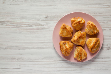 Top view, homemade cottage cheese biscuits on pink plate over white wooden surface. Flat lay, overhead, from above. Copy space.