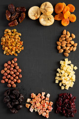 Frame of dried fruits and nuts on black table, top view. Overhead. Copy space.