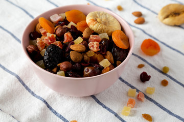 Dried fruits and nut mix in a pink bowl, side view. Closeup.