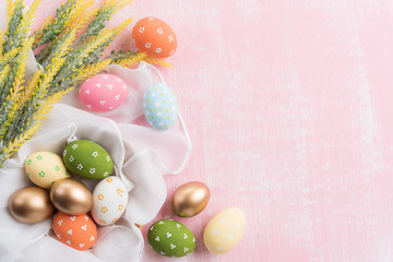 Fototapeta na wymiar Happy easter! Colourful of Easter eggs in nest with flower and Feather on pink wooden background.