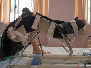 Physiotherapist do stretch exercises on patient's leg, rehabilitation for knee injury in hospithal