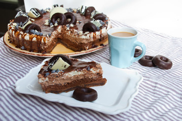 Slice homemade cake three chocolates with piece take out and cup of coffee. Mousse glaze darkness decoration cake.