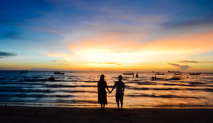 Fototapeta na wymiar Young couple standing on beach when sunset