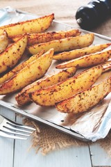 Baked potatoes on tray with black peppers and garlic on rustic wooden board. Vegan food or snack. Healthy food