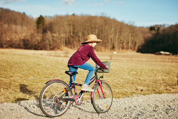 Fototapeta premium Cute little ten year old girl riding bicycle on countryside.
