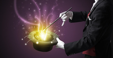 Magician hand conjure with wand  light from a black cylinder