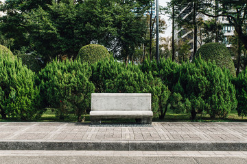 Stone seat in park with pine trees in the background in the area of National Dr. Sun Yat-Sen Memorial Hall in Taipei, Taiwan. © artitwpd