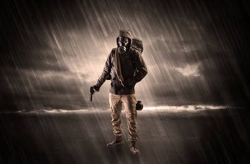 Terrorist in a stormy space with gas mask on his hand and weapons on his arm
