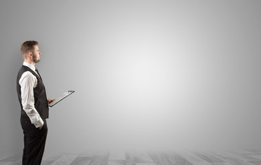 Elegant businessman standing and presenting something in an empty space with floor
