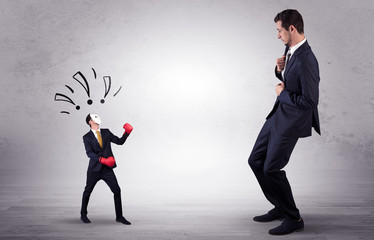 Fototapeta premium Big businessman being afraid of small masked businessman with box gloves in an empty room concept 