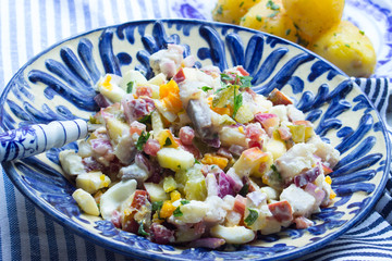 Matjes mit Apfel, Gurke, Zwiebeln und Eiern als Salat angemacht in einer blauen Schüssel