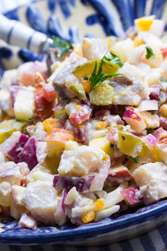Matjes mit Apfel, Gurke, Zwiebeln und Eiern als Salat angemacht in einer blauen Sch&uuml;ssel