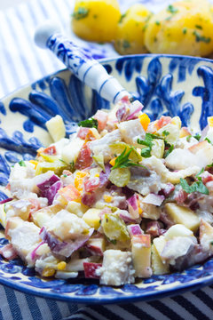 Matjes mit Apfel, Gurke, Zwiebeln und Eiern als Salat angemacht in einer blauen Sch&uuml;ssel