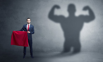 Businessman standing with red cloth on his hand and strong hero shadow on the background

