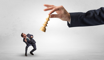 Big hand holding chessman and down little afraid businessman concept in a light space
