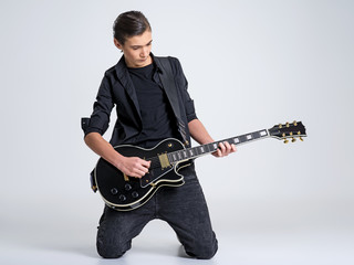 Fifteen years old guitarist with a  black electric guitar. Teenage musician holds guitar