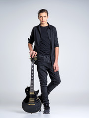 Fifteen years old guitarist with a  black electric guitar.