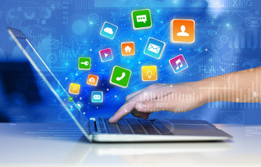 Hand using laptop with bouncing colorful application and global reports and graphs concept
