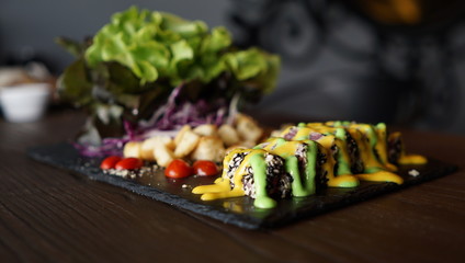 Contrast color of traditional food , Japanese food fusion with Thai food, yellow and green sauce topping on black sushi sesame roll of rice, serve with green vegetable, contrast food menu concept, 