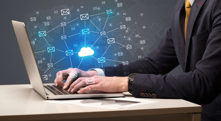 Businessman hand sending a bunch of messages on laptop with cloud computing concept
