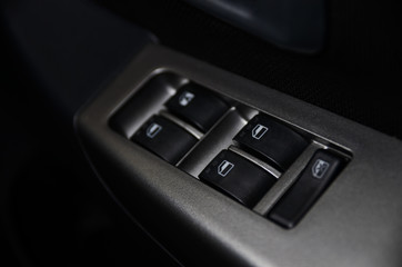Car interior details of door handle with windows controls and adjustments. Car window controls and details