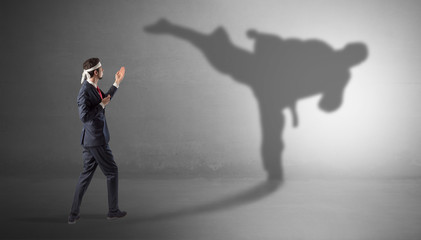 Businessman fighting with his strong karate man shadow
