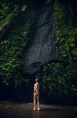 Waterfall Tukad Cepung. Waterfall in Bali. The gorge. A girl in a bathing suit at the waterfall Travel.	