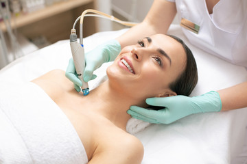 Obraz na płótnie Canvas Pleased woman having dermabrasion procedure of the skin of her neck