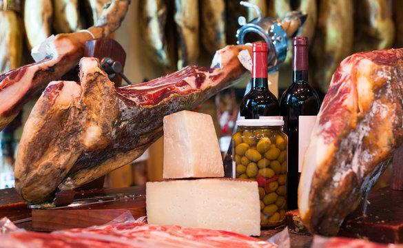 Still life of spanish pork jammon on holder, bottles of wine cheese and olives