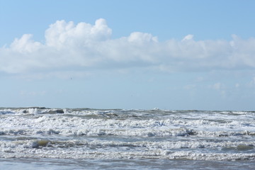 Waves in the sea and cloudy blue sky.