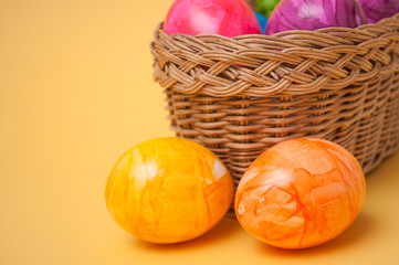 closeup of decorative painted easter eggs in wooden basket on yellow background