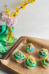 beautiful, bright, very colorful muffins decorated with rainbow cream and candy confetti, on a bright, spring background