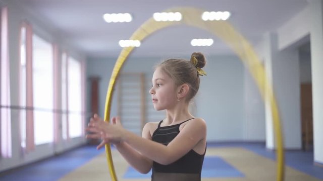 Talented young girl performing gymnastic exercises (palm spin of hula hoop)