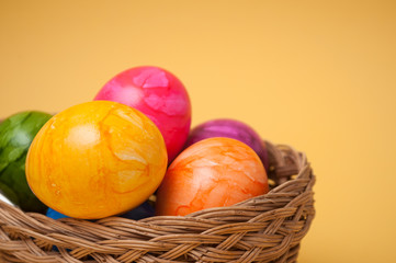 closeup of decorative painted easter eggs in wooden basket on yellow background